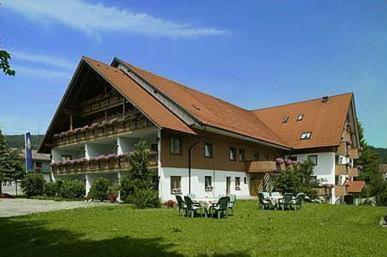 a large building with a brown roof on a green field at Landgasthof Zum Schwarzen Grat in Isny im Allgäu