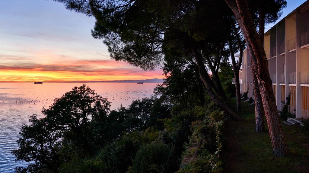 a sunset over the water in front of a building at Hotel Riviera & Maximilian's in Trieste