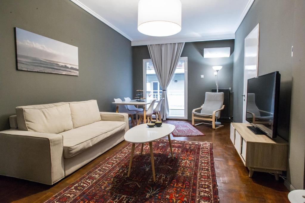 ein Wohnzimmer mit einem Sofa, einem TV und einem Tisch in der Unterkunft Thessaloniki Center Apartment in Thessaloniki