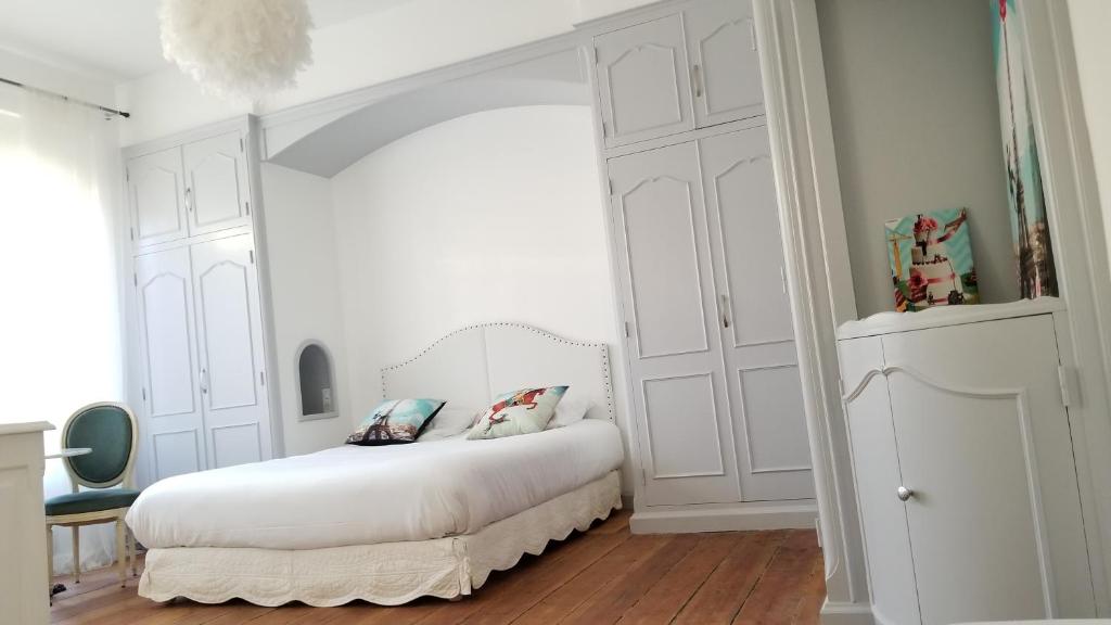 a white bedroom with a white bed with two pillows at La Maison Blanche in Blaye