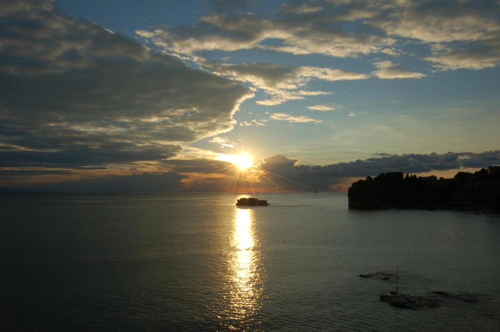 a sunset over a body of water with the sun setting at Hotel Lido Mediterranee in Taormina