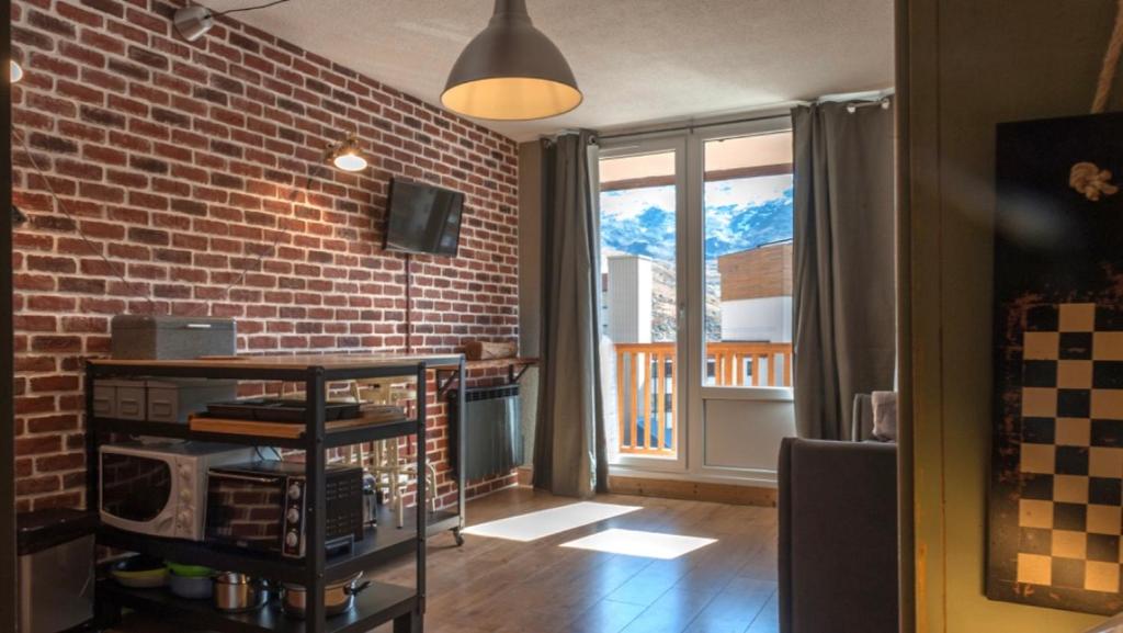 een woonkamer met een bakstenen muur en een raam bij La Roche Blanche in Val Thorens