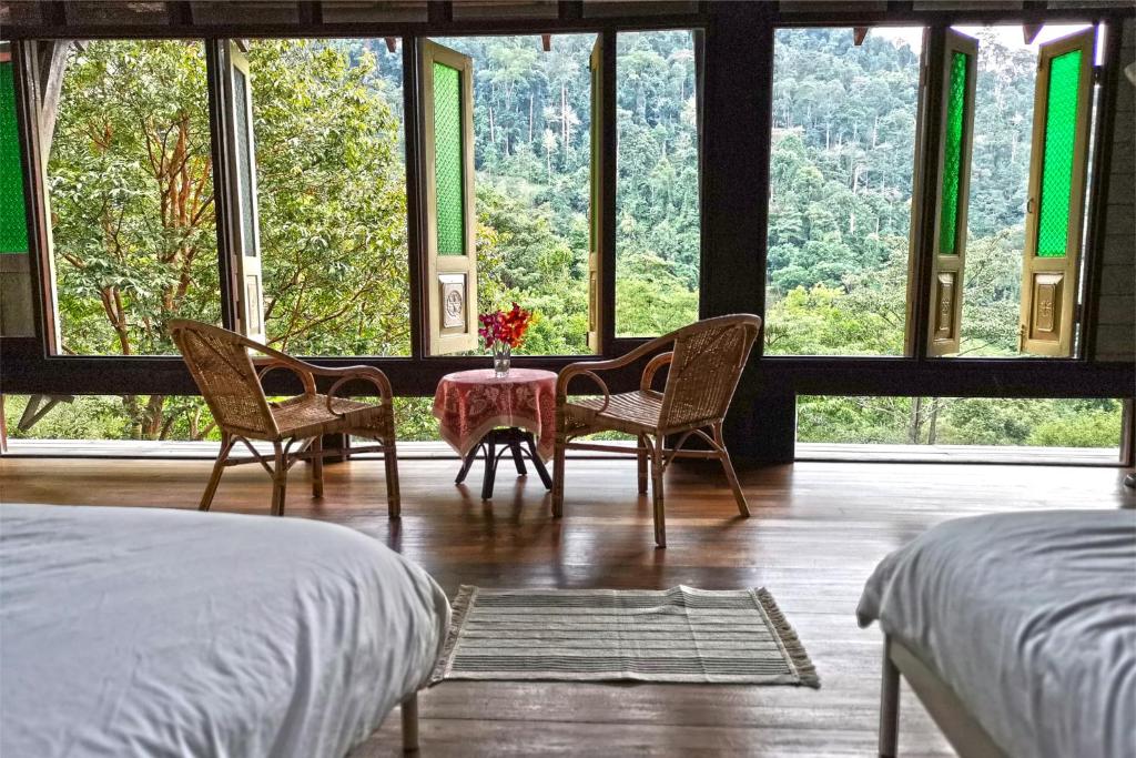 een slaapkamer met 2 stoelen en een tafel voor een raam bij Langit Rimba Resort in Seremban