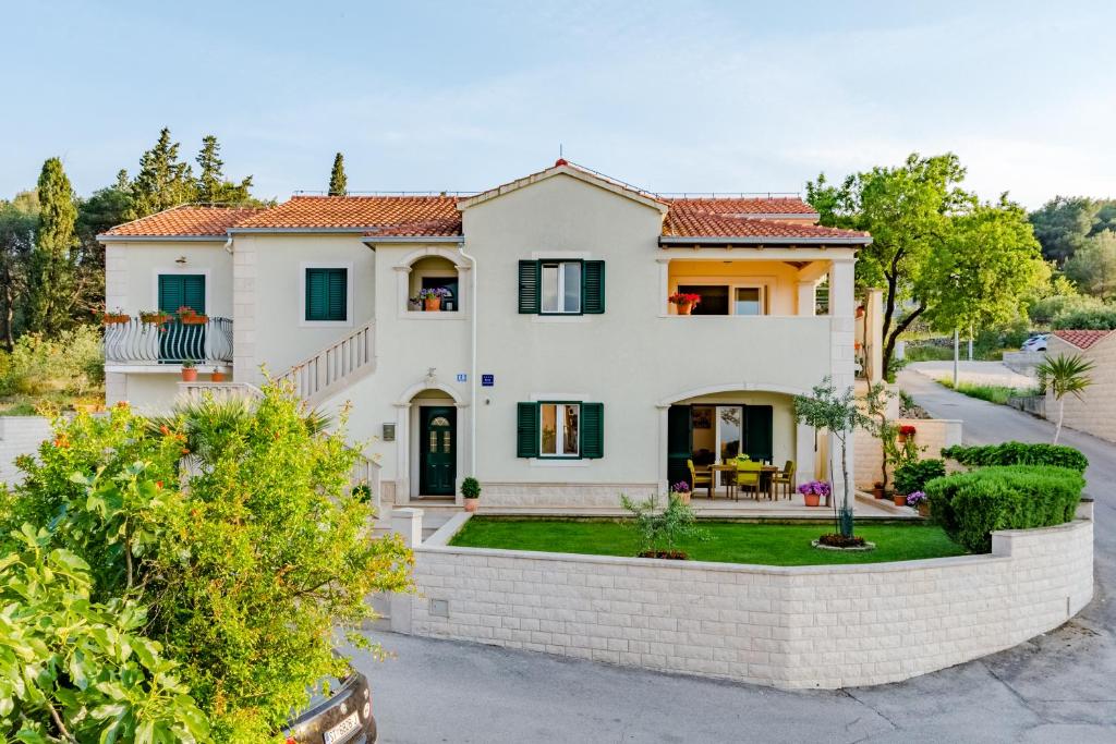 a large white house with a brick wall at Apartment Deni in Supetar