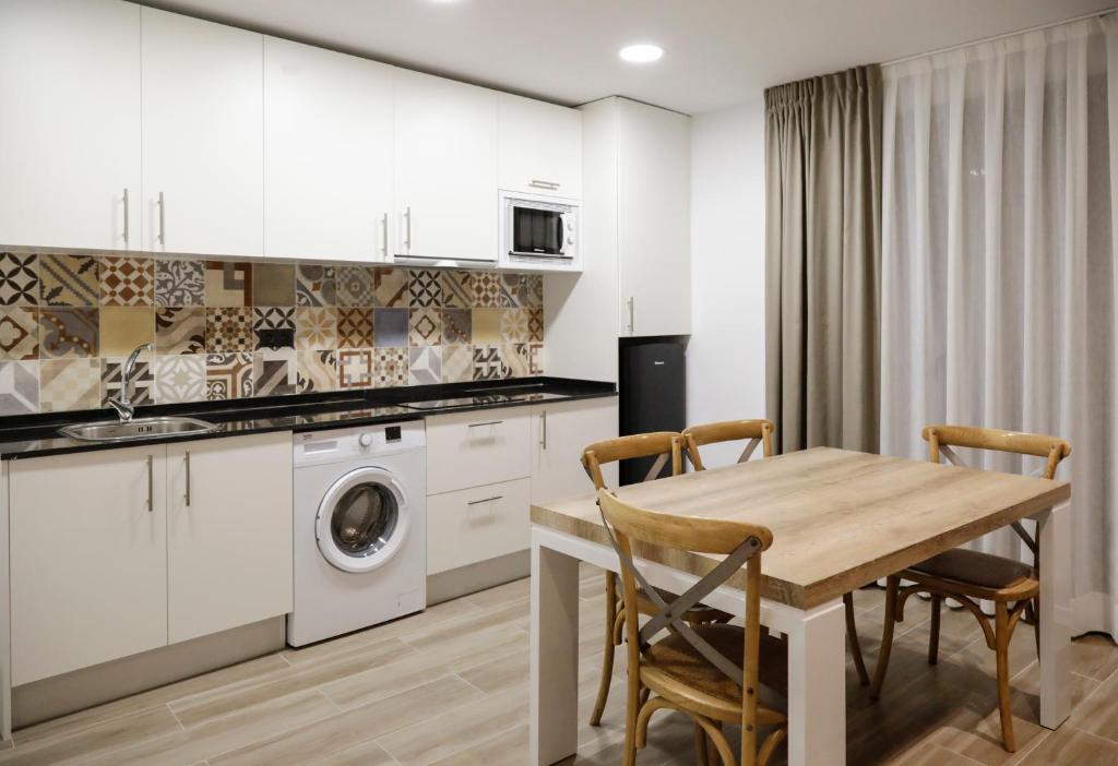 una cocina con armarios blancos y una mesa con sillas. en SM Apartments Station, en Lleida