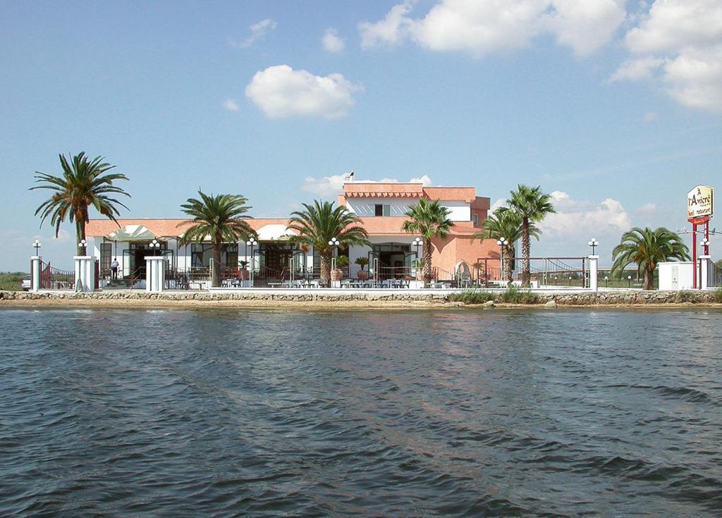 un edificio sulla riva di uno specchio d'acqua di Hotel L' Anicrè a Marina di Varcaturo