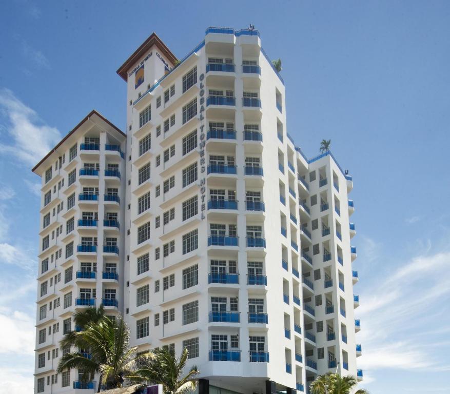 a tall white building with palm trees in front of it at Global Towers Hotel & Apartments in Colombo