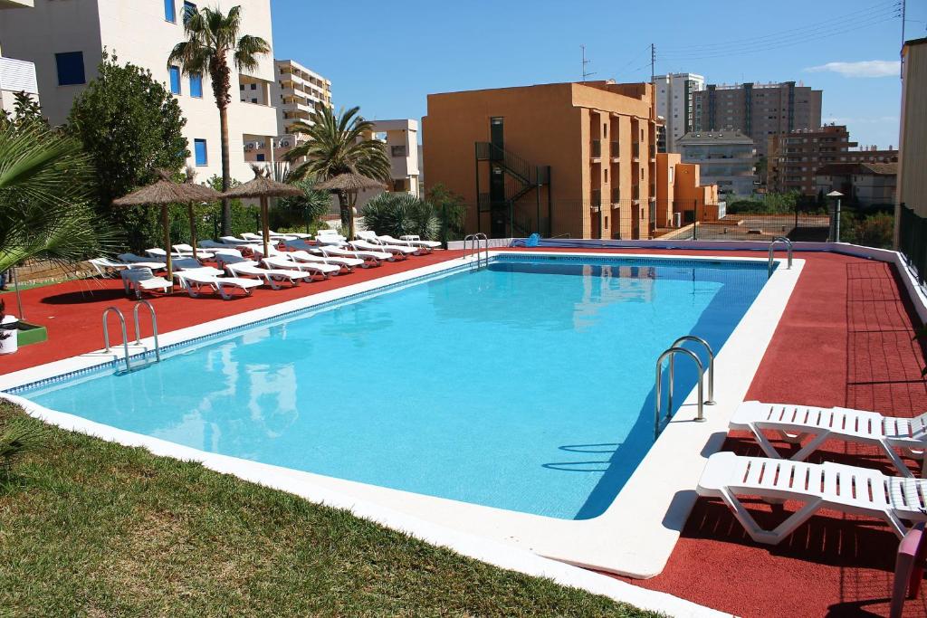 a large swimming pool with lounge chairs and umbrellas at Hotel Jardín in Oropesa del Mar