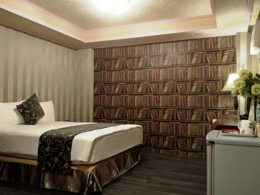a hotel room with a bed and a wall of books at Guan Lun Hotel in Hualien City
