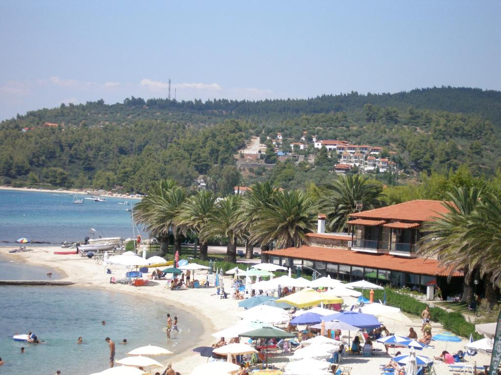 a beach with umbrellas and people in the water at Happy Camp mobile homes in Castello Camping & Summer Resort in Neos Marmaras