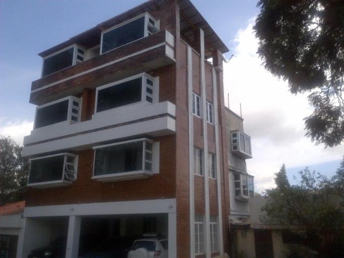 wysoki budynek z czerwonej cegły z białymi oknami w obiekcie Apartamentos Comodos Cerca del Aeropuerto w mieście Gwatemala