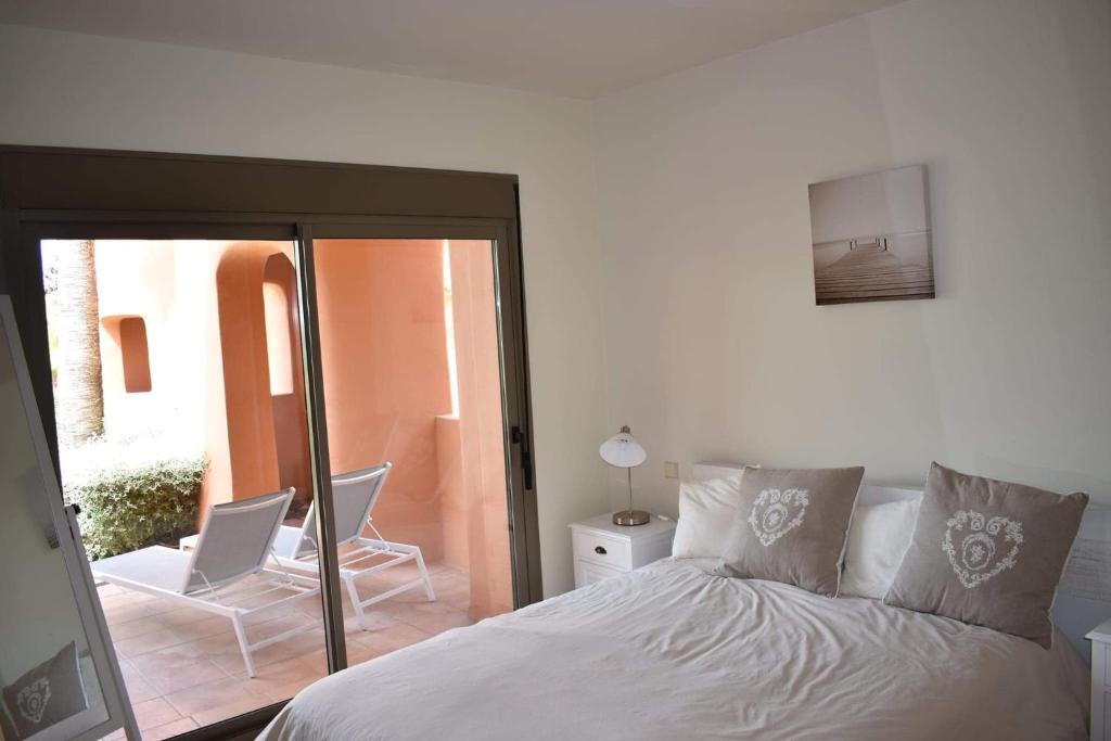 エステポナにある2256-Stunning groundfloor in luxury complex!のベッドルーム1室(ベッド1台、椅子、窓付)