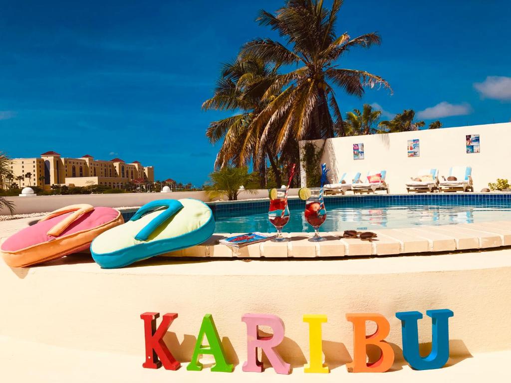 a sign that says karbu next to a swimming pool at Karibu Aruba Boutique Hotel in Palm-Eagle Beach
