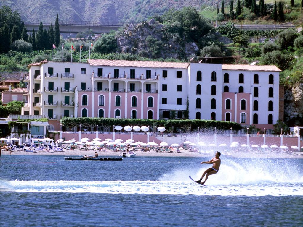 a person water skiing in the water near a beach at Hotel Lido Mediterranee in Taormina