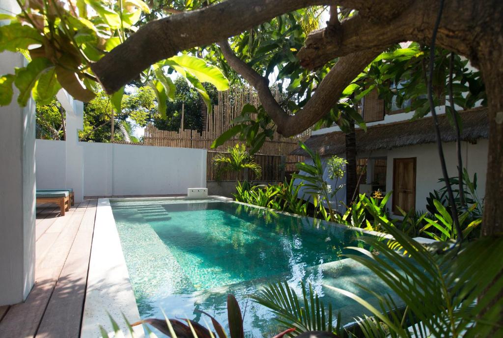 a swimming pool in a garden with a tree at The Mandana Villa Gili Air in Gili Islands