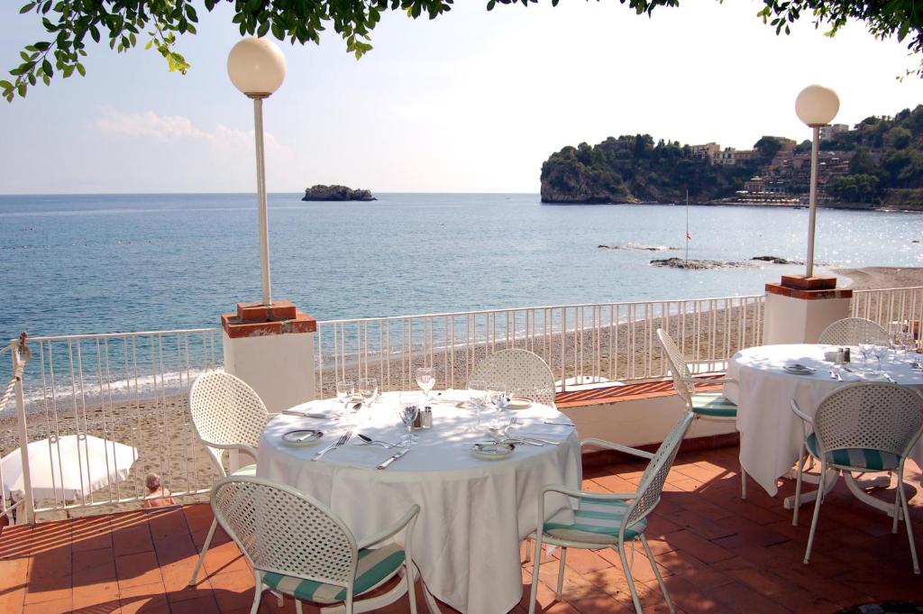 a patio with tables and chairs and a view of the ocean at Hotel Lido Mediterranee in Taormina
