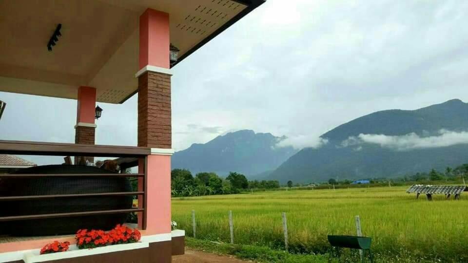a house with a view of a field and mountains at Ban Thung Talay Mok Chiangdao in Chiang Dao