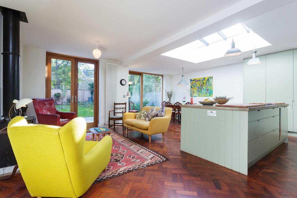 a living room with yellow chairs and a kitchen at Veeve - East London Elegance in London