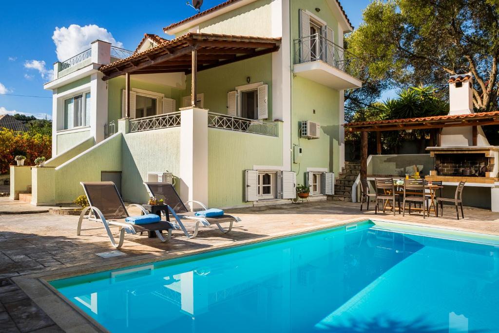 a villa with a swimming pool in front of a house at Bee's Knees Retreat in Pesádha