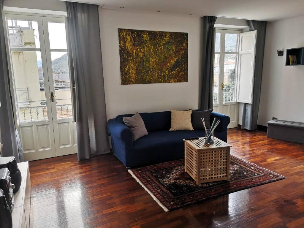 una sala de estar con un sofá azul y una pintura en A casa di Zara, en Termini Imerese