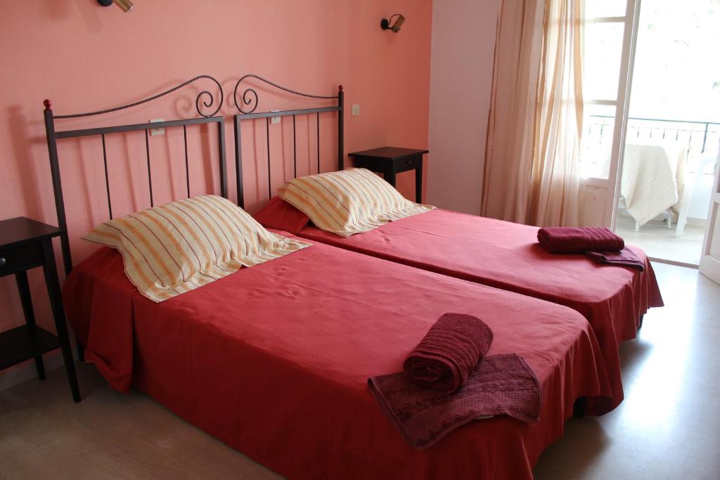 a bedroom with two beds with red sheets and pillows at Natasa and Spiros in Paleokastritsa