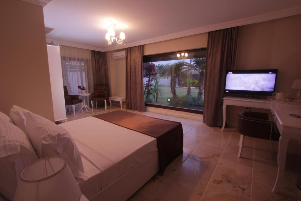 a bedroom with a bed and a flat screen tv at Alaçatı Çınar Boutique Hotel in Alaçatı