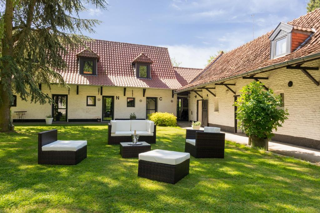 a yard with chairs and tables in the grass at La Ferme Blanche, The Originals Relais (Relais du Silence) in Lompret