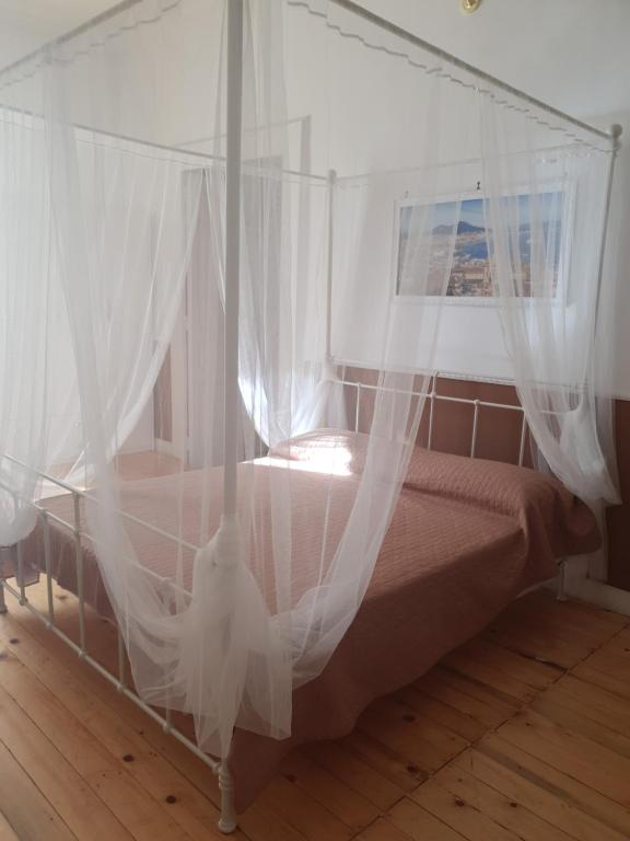 1 dormitorio con cama con dosel y cortinas blancas en B&B La Torretta Chiaia, en Nápoles