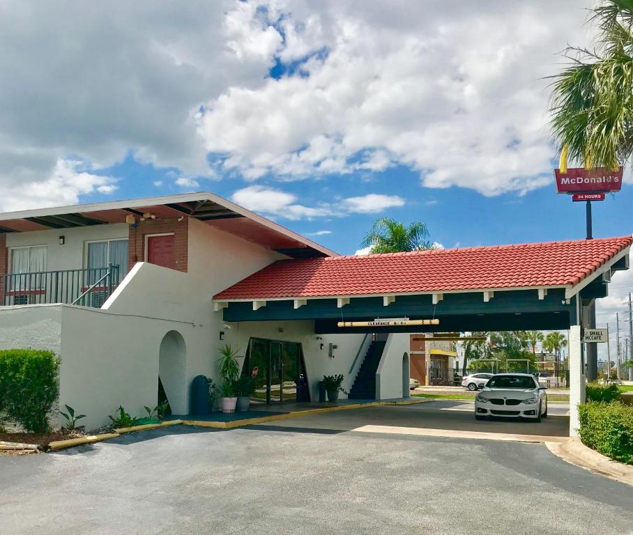 un coche aparcado frente a una gasolinera en Red Carpet Inn Kissimmee, en Kissimmee