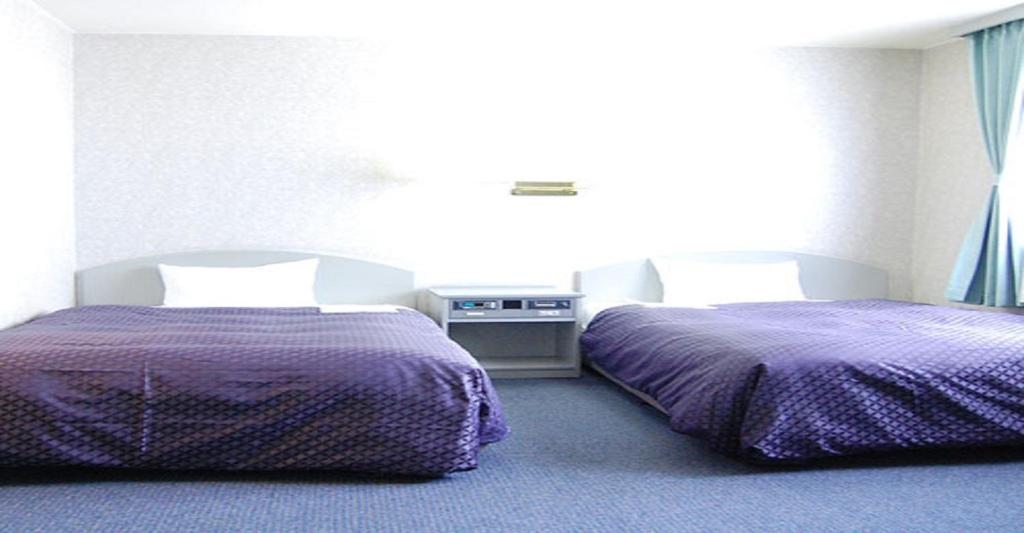 Seagrande Shimizu Station Hotel / Vacation STAY 8208 في شيزوكا: سريرين في غرفة ذات أغطية أرجوانية