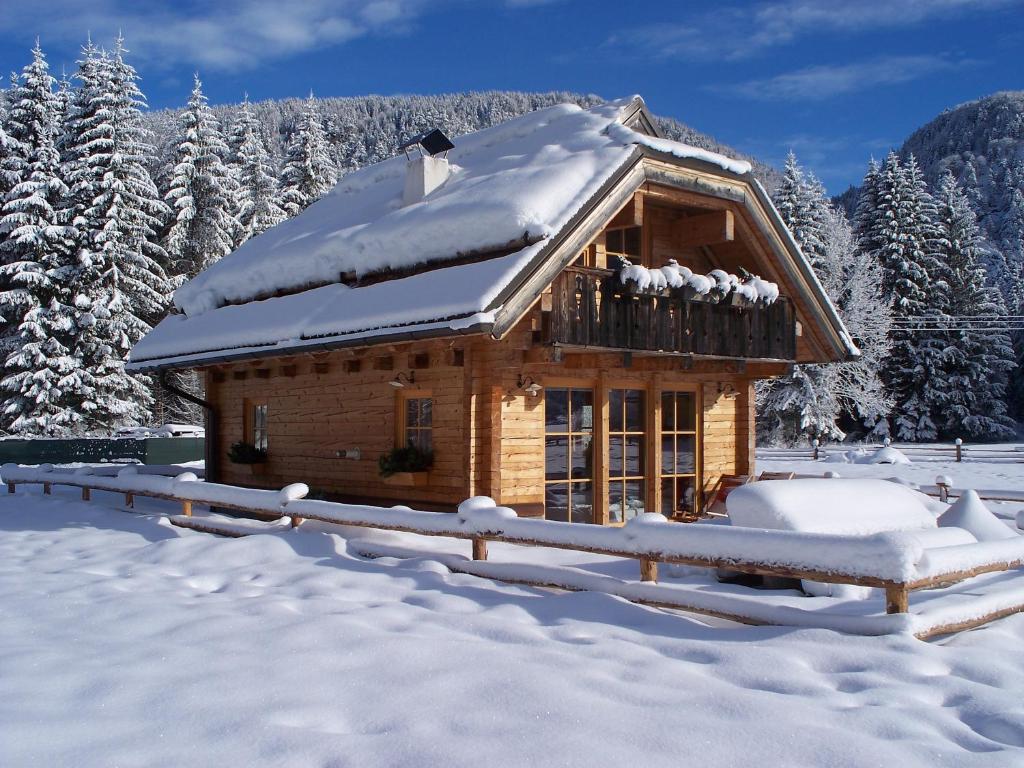 una cabaña de madera en la nieve con árboles nevados en Alpi Giulie Chalets, en Valbruna