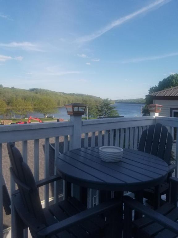 a table and chairs on a deck with a view of the water at Hallowell Rooming House in Hallowell