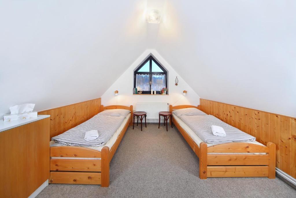 2 camas en una habitación con mesa y ventana en Chalupa Na Desítce en Strážné