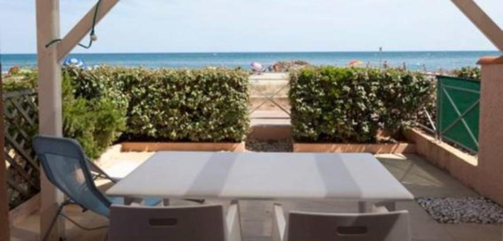 - une table et des chaises blanches sur un balcon donnant sur la plage dans l'établissement Appartement T3 refait à neuf face à la mer, à Frontignan