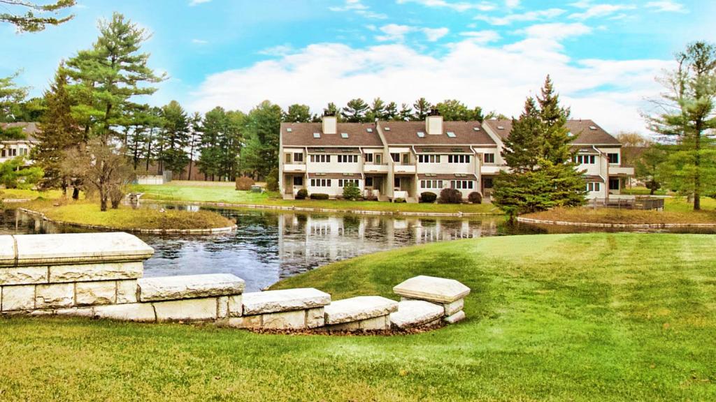 a large house with a pond in front of it at The Ponds at Foxhollow by Capital Vacations in Lenox