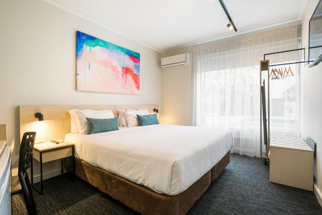 a bedroom with a large bed with a desk and a window at Nightcap at Playford Tavern in Elizabeth