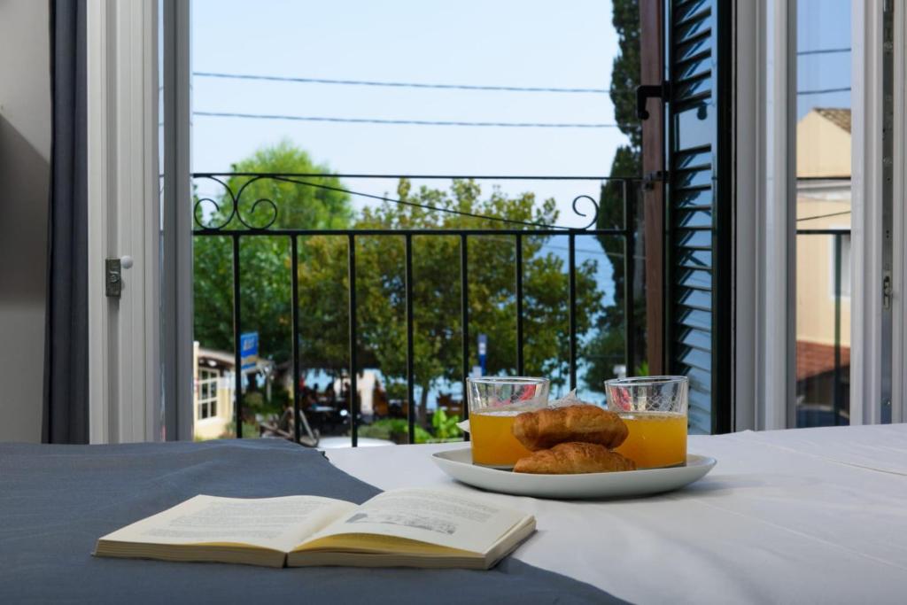 un plato de zumo de naranja y galletas en una mesa con un libro abierto en Dorotea Luxury Rooms, en Ýpsos