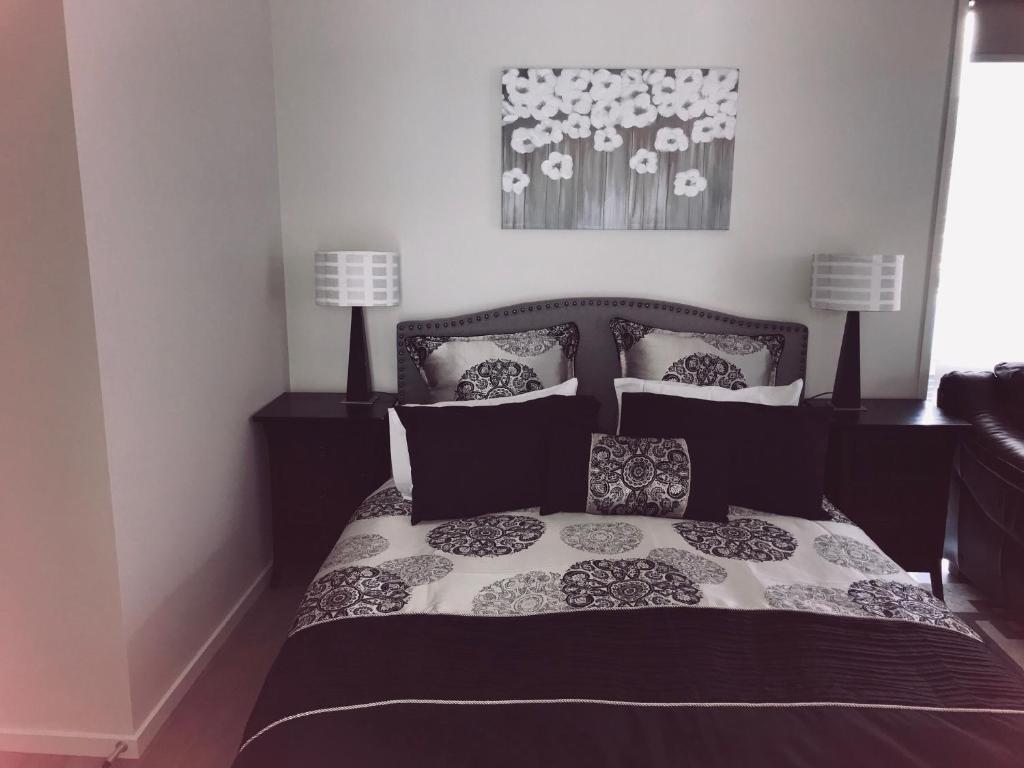 a bedroom with a black and white bed with pillows at Modern Self Contained Apartment in Riverhead in Riverhead