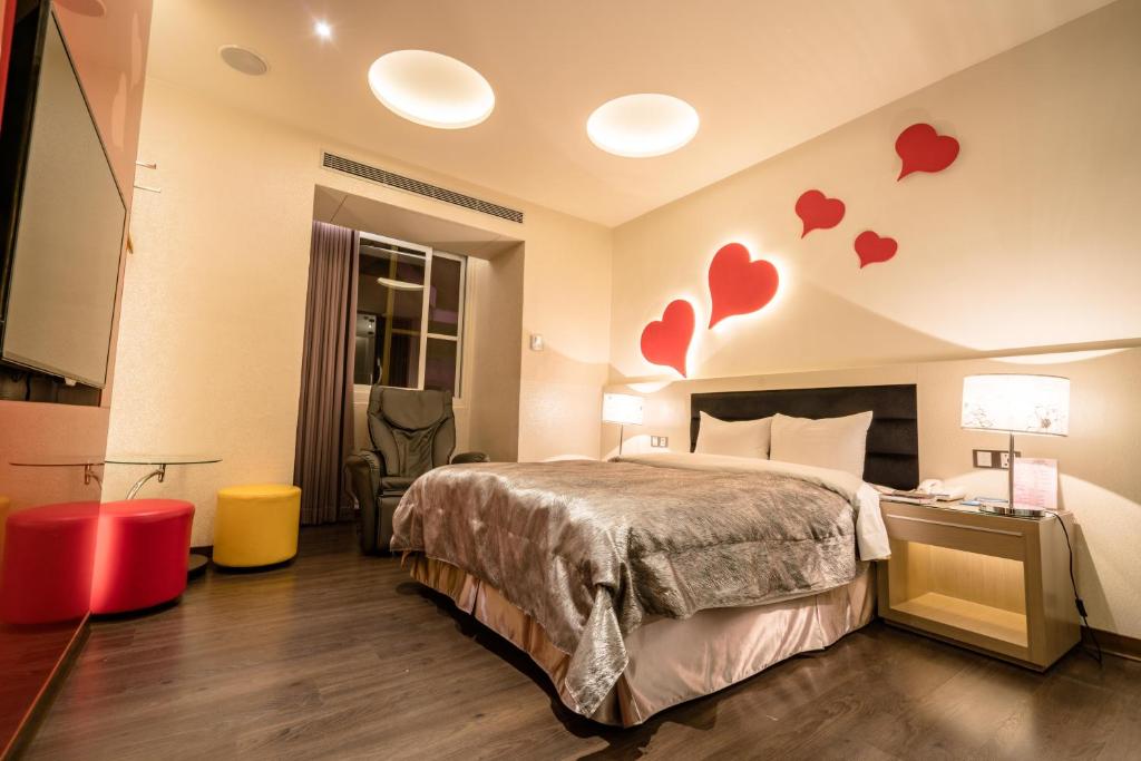 een hotelkamer met een bed en harten aan de muur bij Eusta Motel in Taichung