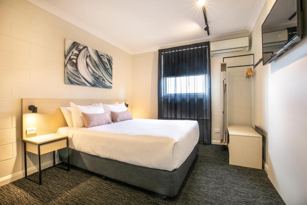 a bedroom with a white bed and white walls at Nightcap at Hendon Hotel in Adelaide
