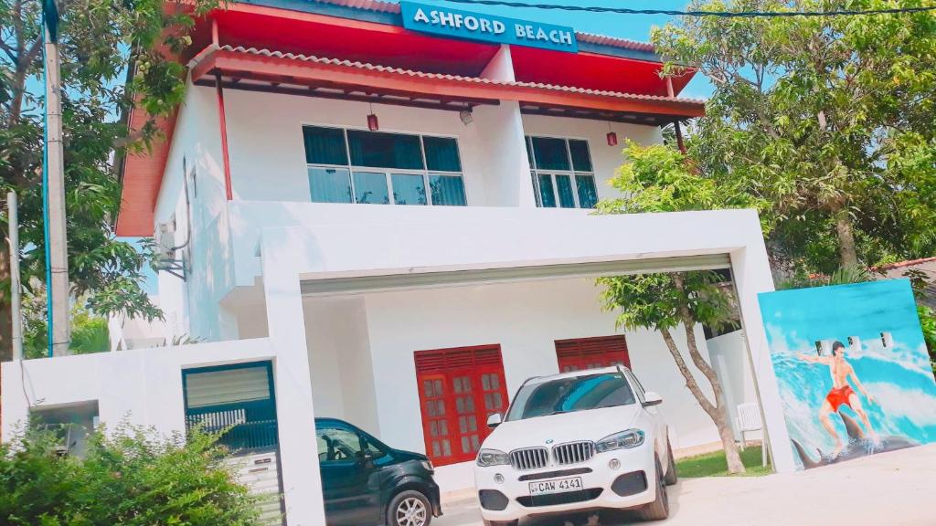 a white building with a car parked in front of it at Ashford Beach in Matara