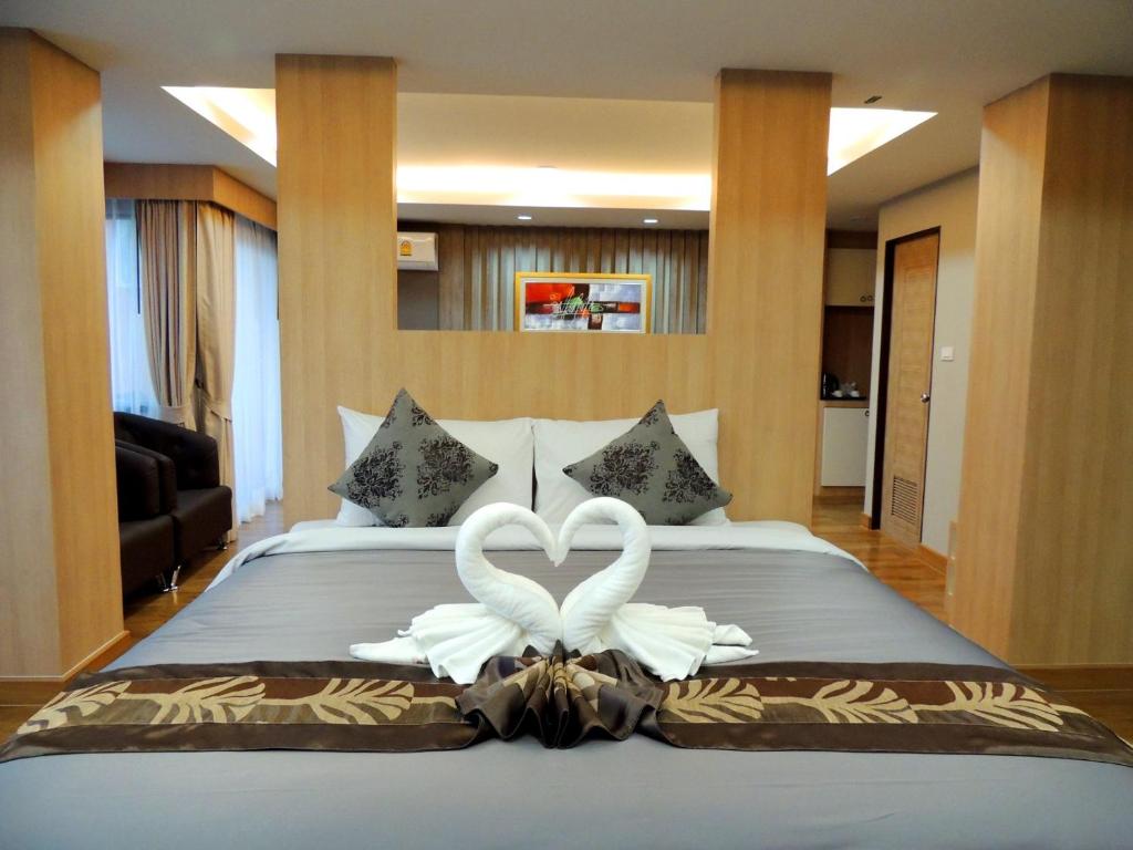 two white swans forming a heart on a bed at The Raise Hotel in Hat Yai