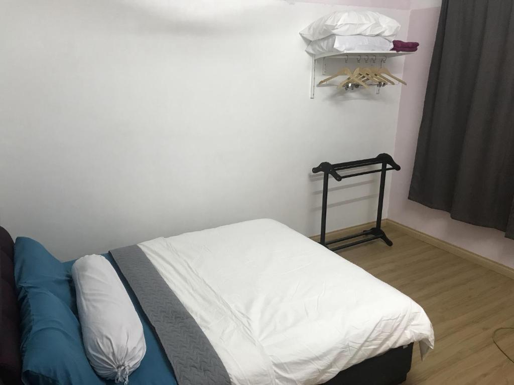 een slaapkamer met een bed met witte lakens en een raam bij Seri Manjung Homestay Wazer Residence in Lumut