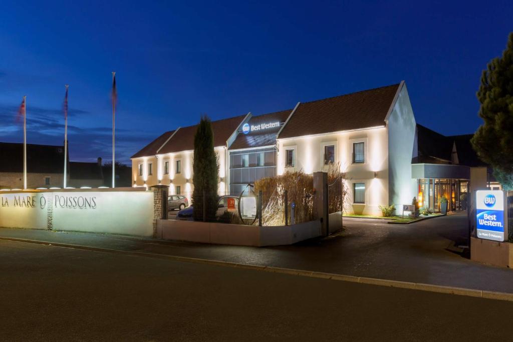 a white building with a sign in front of it at Hotel Best Western La Mare Ô Poissons in Ouistreham