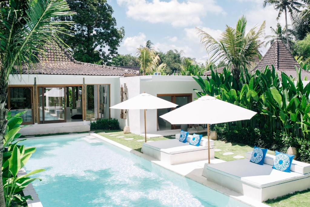 a villa with a swimming pool and two umbrellas at The Apartments Ubud in Ubud