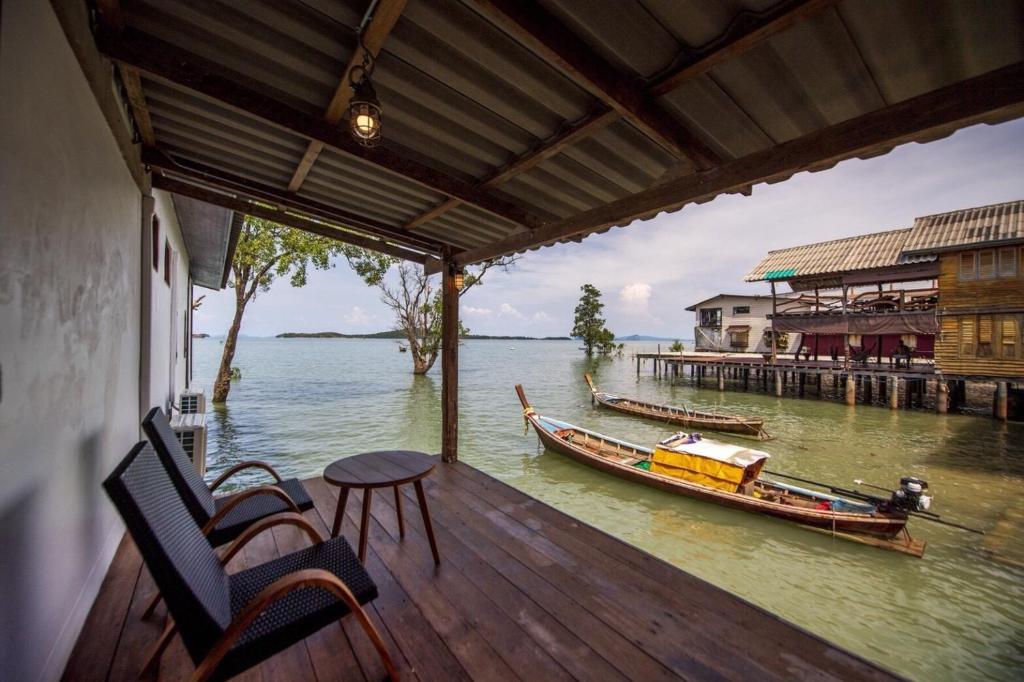 a porch with a table and a boat on the water at Lanta Harbour in Ko Lanta