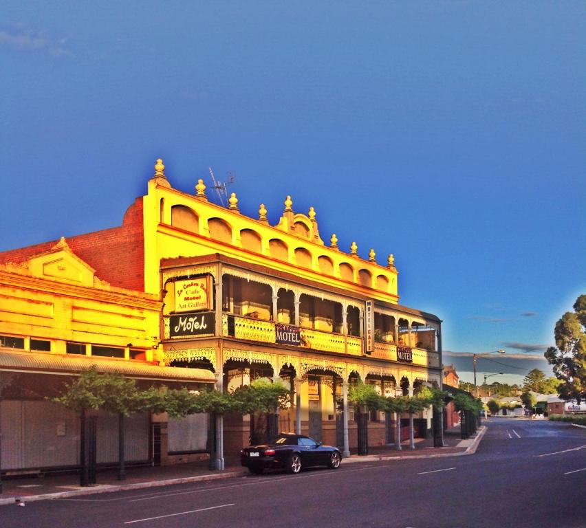 un edificio amarillo con un coche aparcado delante de él en La Cochon Rose Motel, en Saint Arnaud