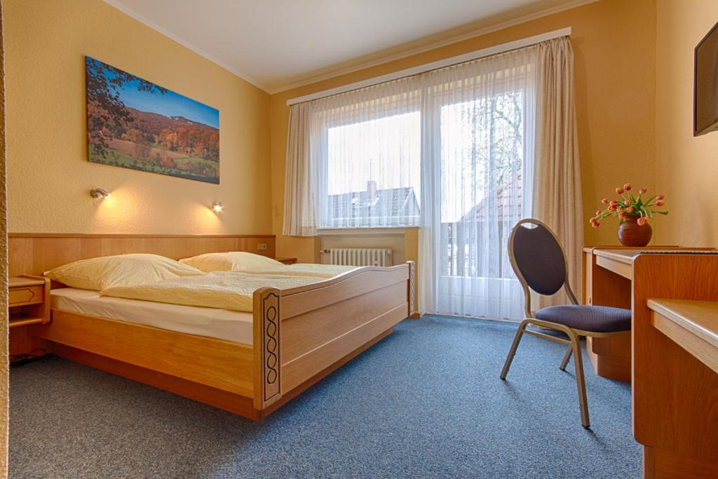 a bedroom with a bed and a chair and a window at Hotel Papp-Mühle in Zersen