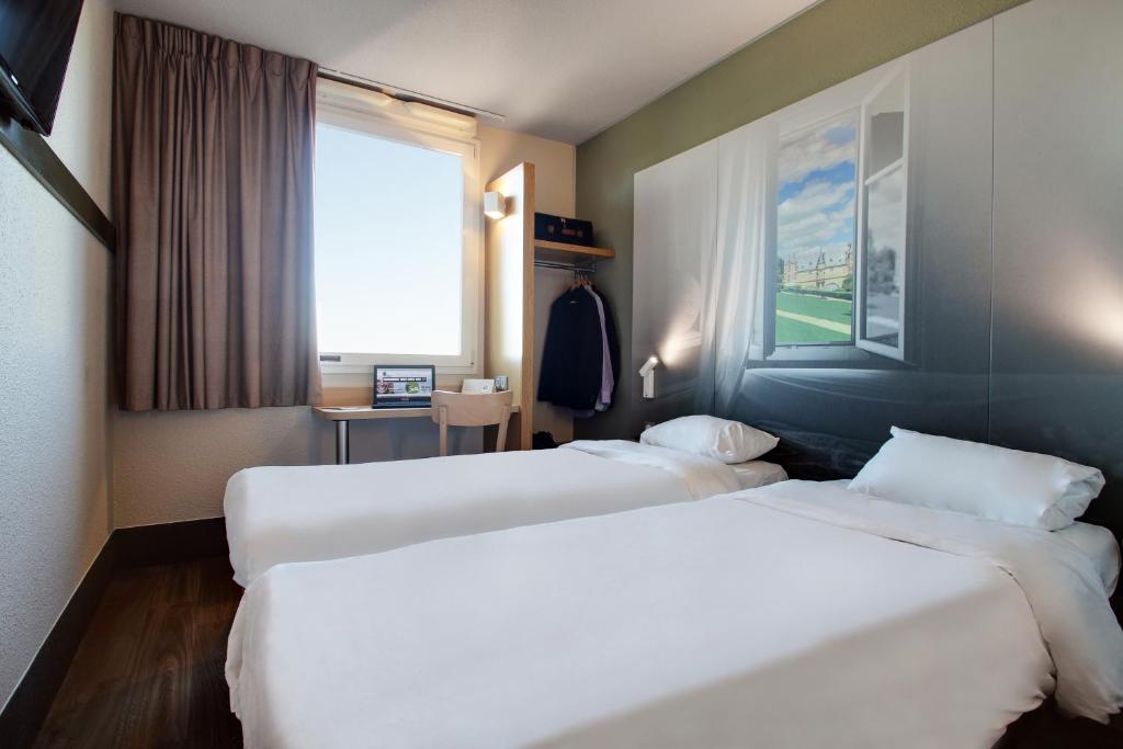 ein Hotelzimmer mit zwei Betten und einem Fenster in der Unterkunft B&B HOTEL Châlons-en-Champagne in Châlons-en-Champagne