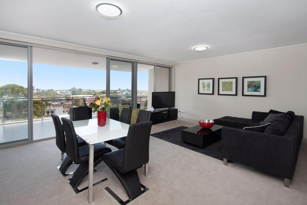 een woonkamer met een tafel en een bank bij The Junction Palais - Modern and Spacious 2BR Bondi Junction Apartment Close to Everything in Sydney